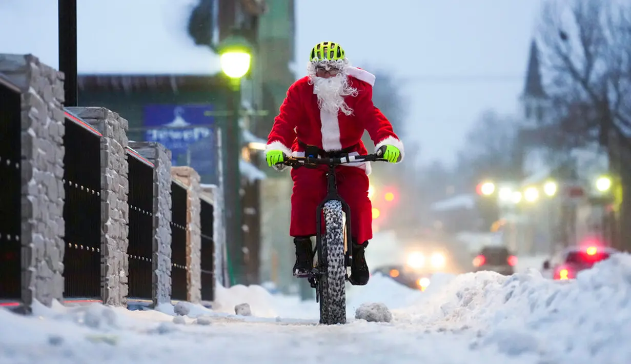Brian Dickie berpakaian seperti Sinterklas saat mengendarai sepedanya melalui jalan-jalan musim dingin pada Malam Natal di Carleton Place, Ontario, Kanada, 24 Desember 2022. (Sean Kilpatrick/The Canadian Press via AP)