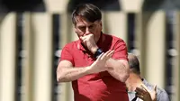 Presiden Brasil Jair Bolsonaro batuk saat berbicara dalam protes karantina dan jarak sosial untuk memerangi wabah virus corona COVID-19 di Brasilia, Brasil, 19 April 2020. Bolsonaro sempat dinyatakan negatif COVID-19 setelah beberapa ajudannya positif kena virus. (Sergio LIMA/AFP)