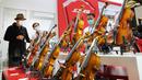 Seorang staf (kedua dari kiri) memperkenalkan biola kepada pengunjung pada ajang Music China 2020 di Shanghai New International Expo Center, China, 28 Oktober 2020. Music China 2020 diikuti lebih dari 1.000 industri musik dari 11 negara dan kawasan dengan produk-produk baru mereka. (Xinhua/Fang Zhe)