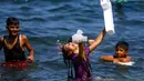 Seorang gadis Palestina tertawa sambil memegang ubur-ubur saat bermain bersama teman-temanya di laut Mediterania dekat kamp pengungsi al-Shati di Kota Gaza (3/7). (AFP Photo/Mohammed Abed)