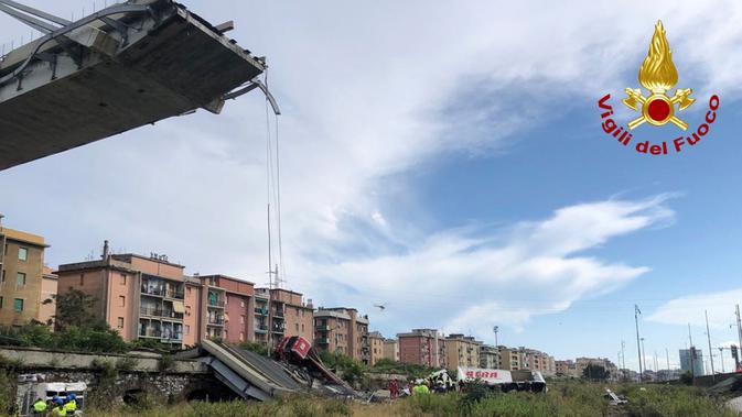 Tim penyelamat berada di antara puing-puing jembatan jalan raya Morandi yang ambruk di kota Genoa, Italia, Selasa (14/8). Mobil-mobil jatuh dari jembatan serta puing-puing tiang ke arah rel kereta. (Vigili Del Fuoco via AP)