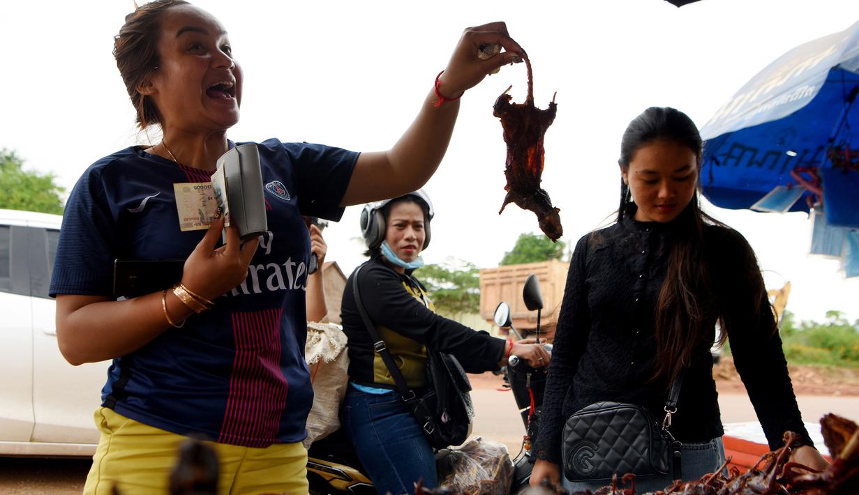 Seorang wanita saat membeli tikus bakar di sebuah kios di provinsi Battambang, Kamboja (8/8/2019). Tikus bakar yang tusuk sate harganya masing-masing 0,25 USD atau sekitar 3500 rupiah. (AFP Photo/Tang Chhin Sotthy)