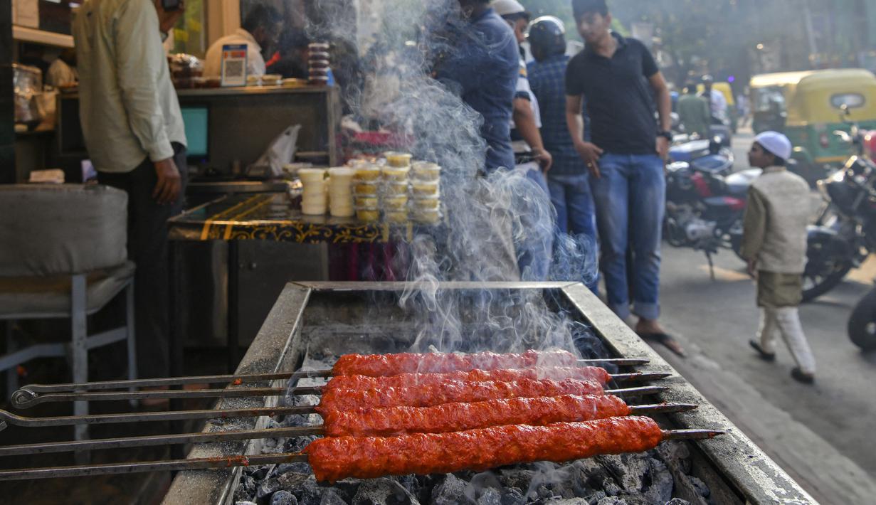 Juru masak (tidak digambarkan) menyiapkan kabab di sebuah restoran untuk umat Muslim untuk berbuka puasa pada hari pertama bulan suci Ramadhan di Bangalore. Masjid dan jalan-jalan pasar penuh dengan keramaian malam, tergoda oleh aroma manisan manis untuk berbuka puasa. (Manjunath Kiran / AFP)