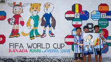 Anak-anak berpose di depan mural yang menampilkan turnamen sepak bola Piala Dunia 2026 di Polewali Mandar, Sulawesi Barat, Kamis 11 Juni 2026. (Muhammad SALIM/AFP)