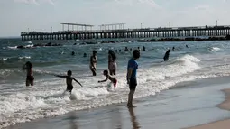 Orang-orang menikmati hari di Coney Island, salah satu tujuan pantai paling populer di wilayah Brooklyn di New York City (29/6/2022). Menyusul tenggelamnya dua pemuda di Rockaway dua minggu lalu, Gubernur Kathy Hochul menaikkan gaji penjaga pantai untuk menarik lebih banyak pelamar ke pantai negara bagian. (Spencer Platt/Getty Images/AFP)