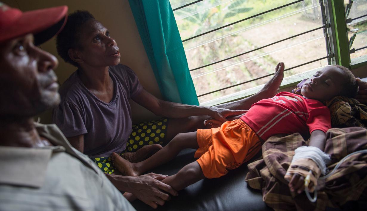 Sepasang suami istri menemani anak mereka yang sedang dirawat di klinik setempat di desa Ayam distrik Asmat, di provinsi Papua Barat (26/1). Jumlah tersebut terhitung sejak September 2017 hingga 24 Januari 2018. (AFP/Bay Ismoyo)