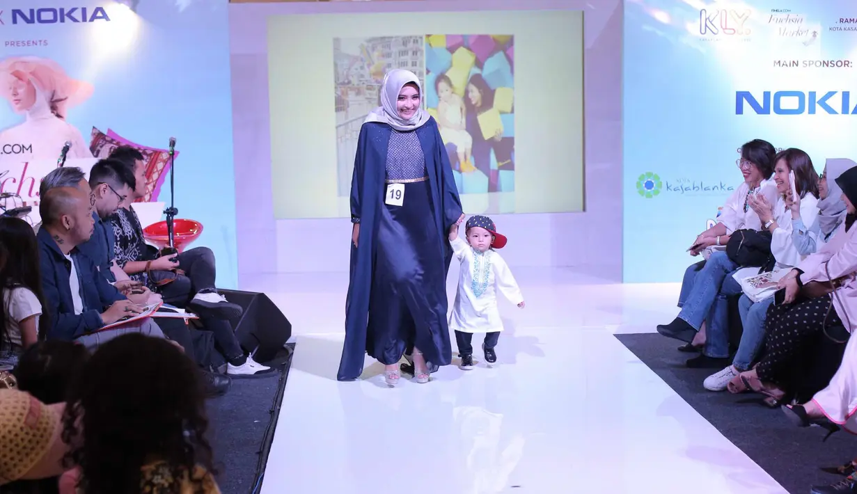 Seorang ibu bersama anaknya berjalan di atas catwalk dalam fashion show Fabalous Mom and Kids 2018 di Fimela Fuchsia Market 2018 di Kota Kasablanka, Jakarta (27/5). (Liputan6.com/Faizal Fanani)