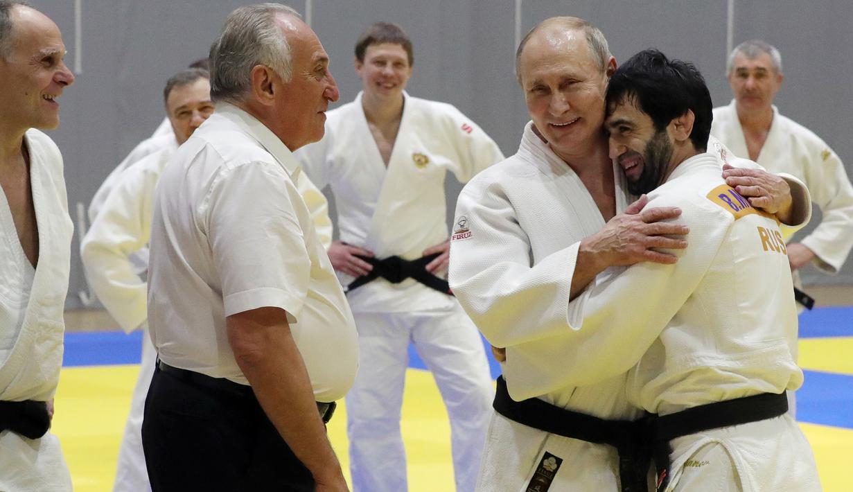 Presiden Rusia, Vladimir Putin memeluk atlet judo nasional Rusia saat mengambil bagian dalam sesi latihan di Sochi, Kamis (14/2). Judo merupakan salah satu olahraga kegemaran Putin yang telah digeluti sejak masa muda. (Mikhail KLIMENTYEV/SPUTNIK/AFP)