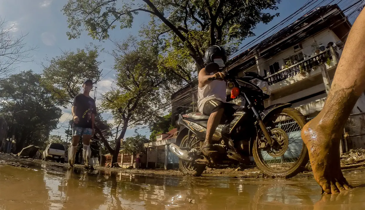 Warga berjalan di sebuah jalan yang tertutup lumpur akibat banjir yang dipicu Topan Vamco di Manila, Filipina (13/11/2020). Pemerintah Filipina pada Jumat (13/11) mengatakan Topan Vamco, yang memicu banjir besar dan tanah longsor menelan sedikitnya 14 korban jiwa. (Xinhua/Rouelle Umali)