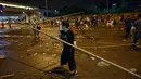 Seorang pria membersihkan bambu bekas barikade setelah demonstrasi menolak RUU ekstradisi di Hong Kong (13/6/2019). Lalu lintas telah dipulihkan di jantung Hong Kong sehari setelah bentrokan antara polisi dan pengunjuk rasa yang menolak RUU Ekstradisi . (AFP Photo/Hectro Retamal)