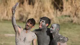 Tiga pasukan Irak berselfie dengan tubuh dipenuhi belerang di Hammam al-Ali, Mosul, Irak, 9/11). Di tengah perang melawan ISIS, mereka melepaskan penat dan lelah dengan berenang di Kolam belerang. (REUTERS/Alaa Al-Marjani)