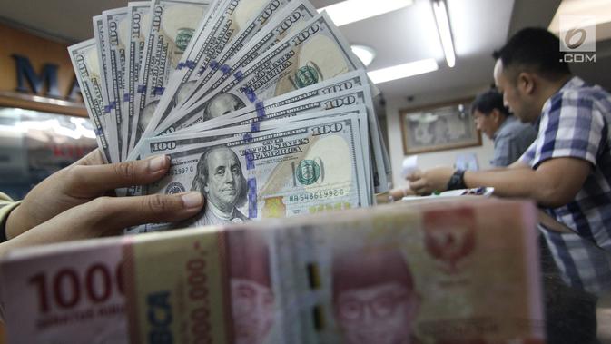 Teller menunjukkan uang dolar dan rupiah di penukaran uang di Jakarta, Junat (23/11). Nilai tukar dolar AS terpantau terus melemah terhadap rupiah hingga ke level Rp 14.504. (Liputan6.com/Angga Yuniar)