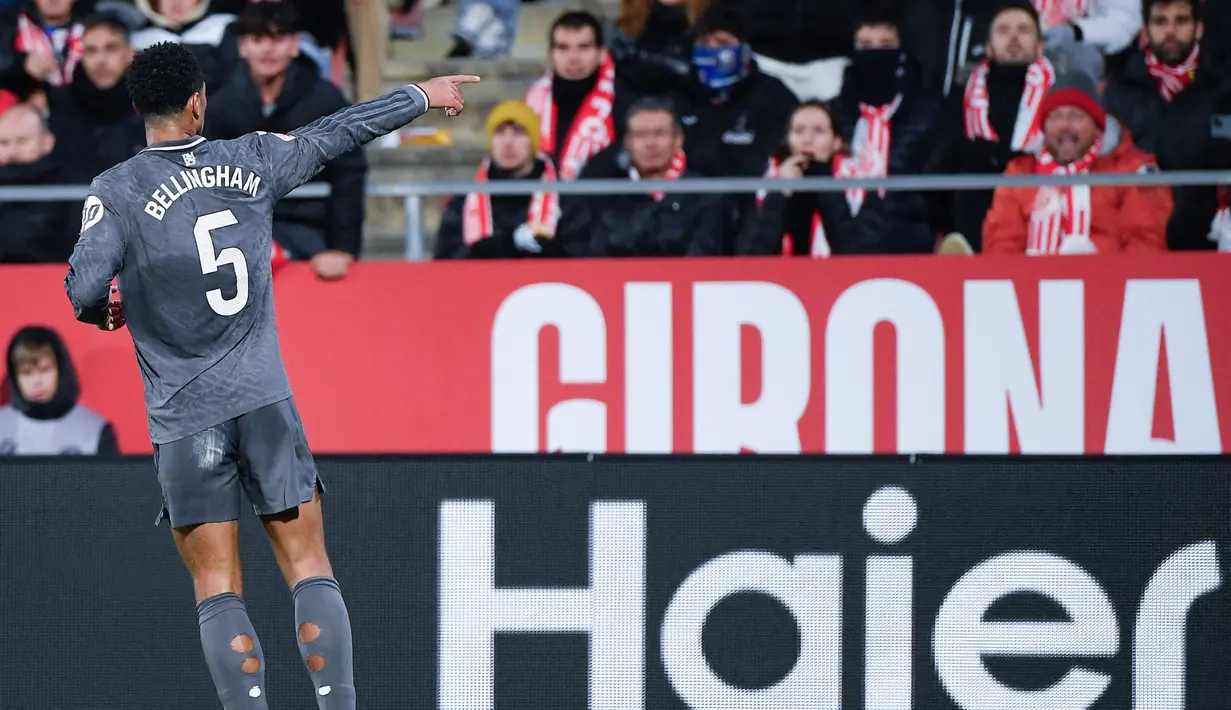 Pemain Real Madrid, Jude Bellingham, melakukan selebrasi di depan suporter Girona pada laga pekan ke-16 Liga Spanyol di Stadion Montilivi pada Sabtu (7/12/2024). (AFP/Josep Lago)