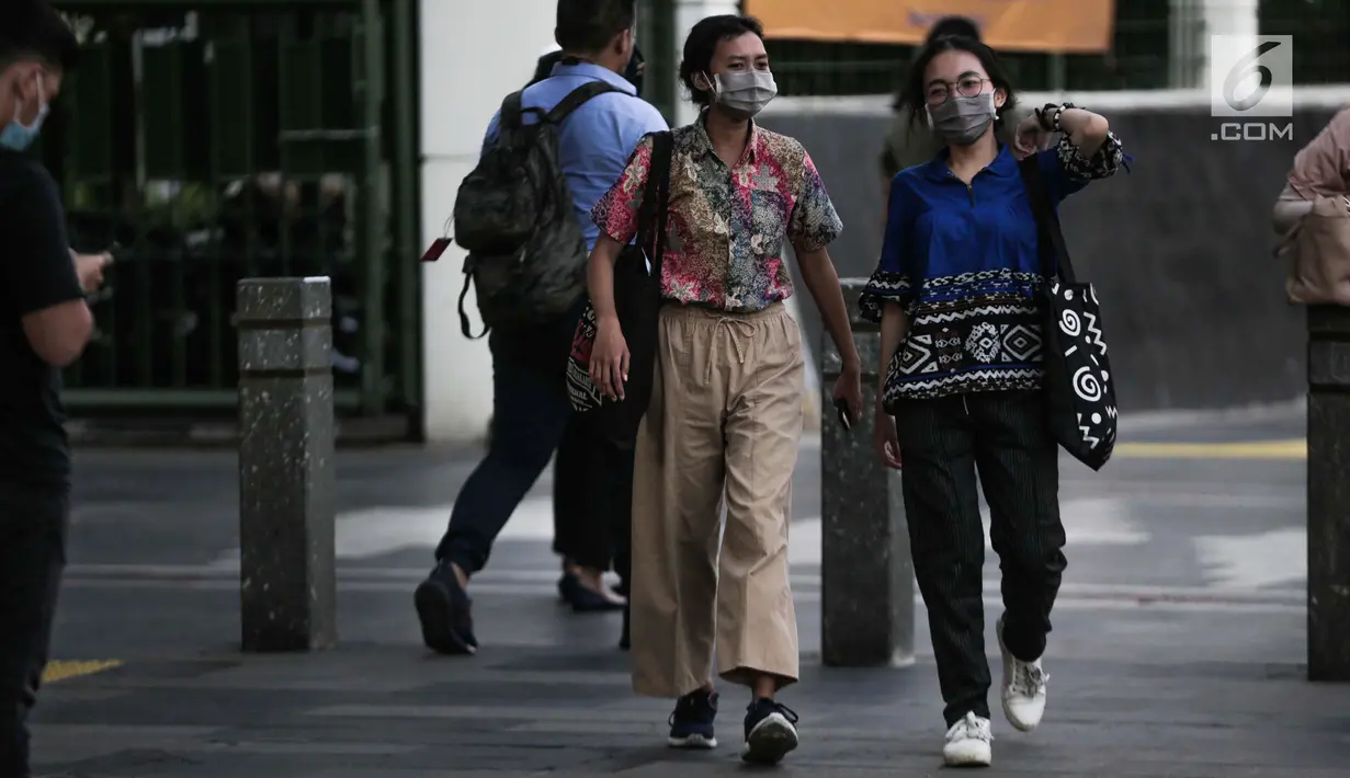 Dua wanita berjalan mengenakan masker pelindung untuk menghindari polusi udara buruk di Jakarta, Rabu (17/7/2019). Dinkes DKI menyarankan masyarakat untuk menggunakan masker saat beraktivitas untuk mencegah dampak polusi udara pada tubuh. (Liputan6.com/Faizal Fanani)