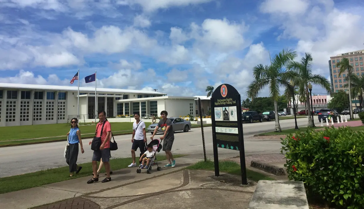 Sebuah keluarga menyusuri jalanan di Hagatna, Guam, Rabu (9/8). Meskipun suasana ketegangan di kawasan itu meningkat terkait ancaman bom nuklir Korea Utara, warga Guam tetap beraktivitas seperti biasa. (AP Photo/Grace Garces Bordallo)
