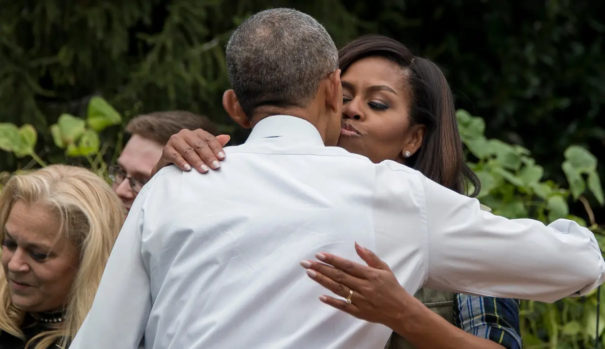 Ibu negara AS Michelle Obama berpelukan dengan sang suami Presiden AS, Barack Obama saat memanen ubi jalar di kebun Gedung Putih, Washington, (6/10). (AFP Photo/Jim Watson)