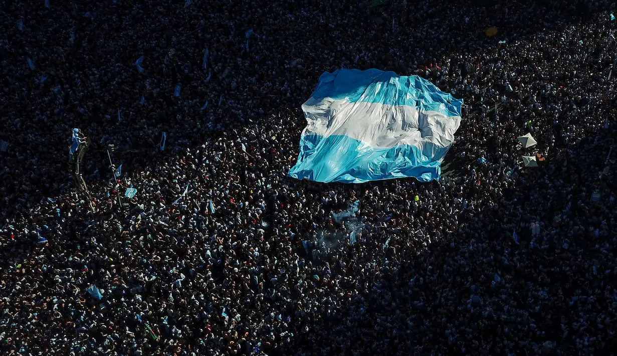 Bendera Argentina terlihat saat suporter merayakan kemenangan Argentina atas Prancis pada pertandingan sepak bola final Piala Dunia Qatar 2022 di Buenos Aires, Argentina, 18 Desember 2022. Argentina menang 4-2 dalam drama adu penalti setelah pertandingan berakhir imbang dengan skor 3-3. (AP Photo/Victor R. Caivano)