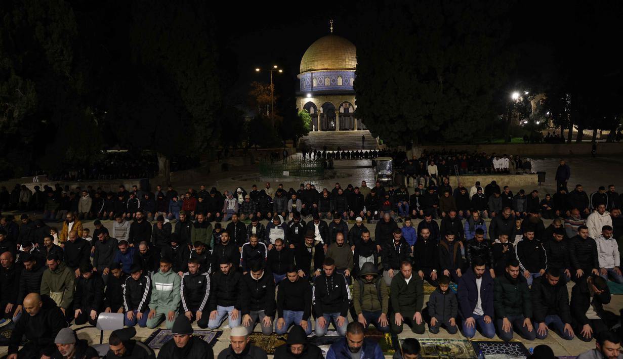 Ibadah berlangsung di bawah pengawalan ketat kepolisian Israel yang berjaga di titik-titik strategis dalam kompleks dan Kota Tua. Tampak dalam foto, para jamaah Muslim Palestina melaksanakan salat Tarawih pada malam pertama bulan suci Ramadan di dekat Kubah Batu, kompleks Masjid Al-Aqsa, Kota Tua Yerusalem pada 17 Februari 2026. (AHMAD GHARABLI/AFP)