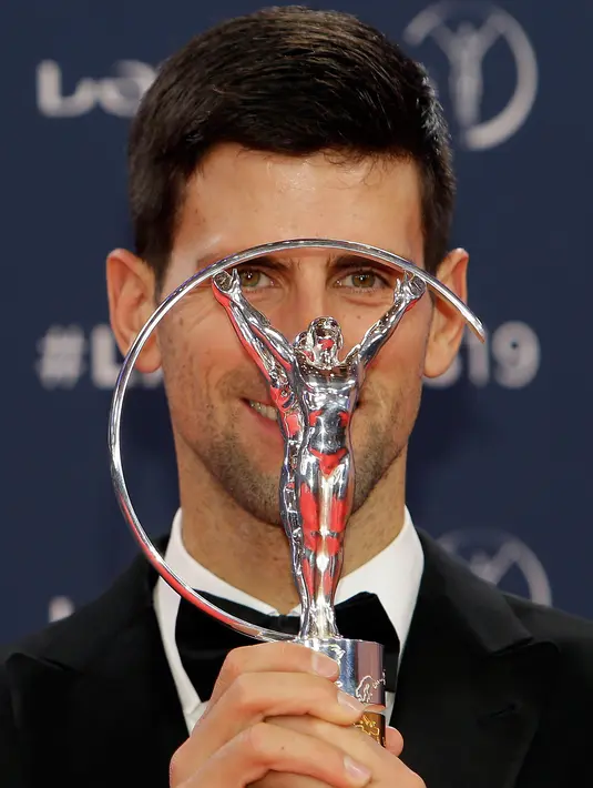 Petenis Serbia, Novak Djokovic berpose dengan trofi World Sportsman of the Year dalam ajang Laureus World Sports Awards 2019 di Monako, Senin (18/2). Sementara itu, gelar World Sportswoman of the Year diraih pesenam AS, Simone Biles. (AP/Claude Paris)