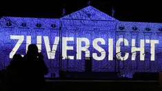 Pengunjung menikmati pemandangan Istana Bellevue yang diterangi proyeksi cahaya bertuliskan "Zuversicht", yang bermakna keyakinan, di Berlin, ibu kota Jerman, pada 17 Desember 2020. Pertunjukan cahaya bertema "Lichtblick" (Seberkas Harapan) ini digelar di Istana Bellevue di Berlin. (Xinhua/Shan Yuqi