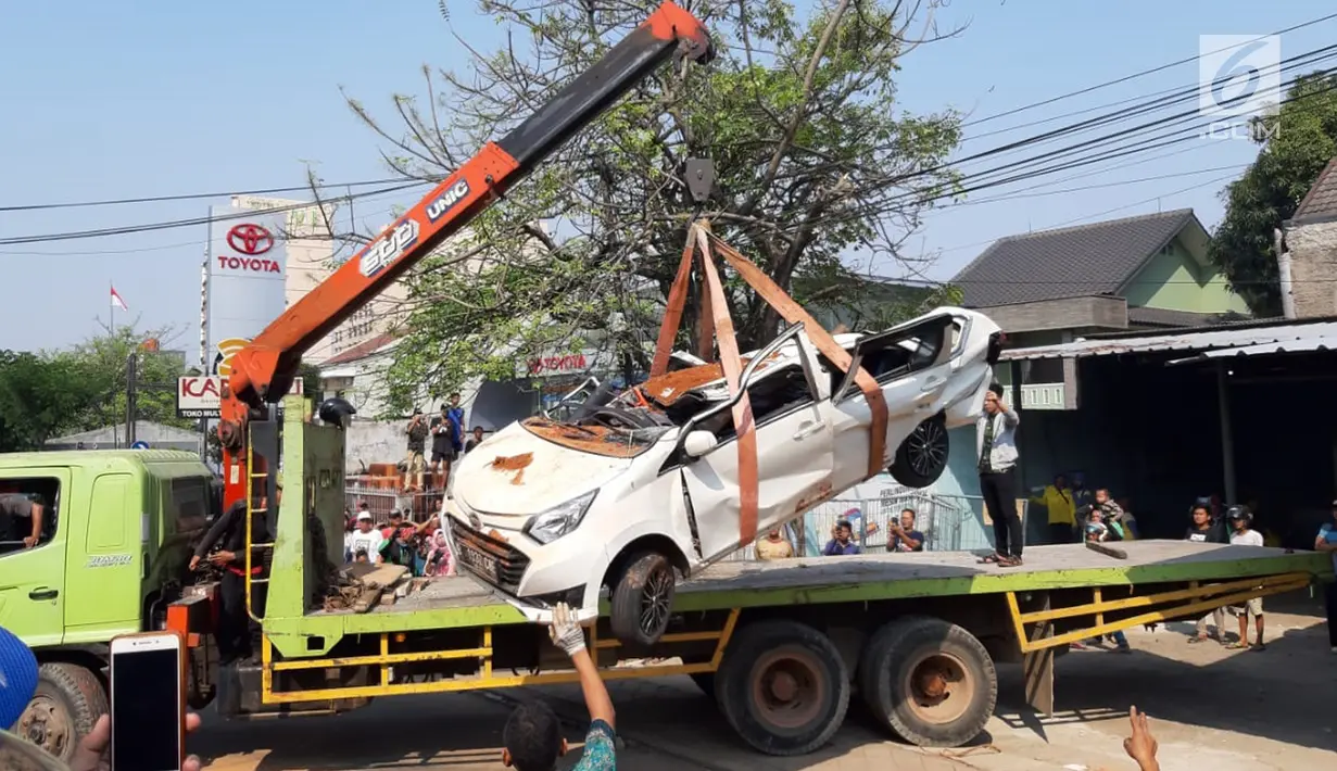 Petugas derek mengevakuasi bangkai mobil kecelakaan maut yang hancur tertindih badan truk muatan tanah di Karawaci, Tangerang, Kamis (1/8/2019). Lima orang penumpang minibus menjadi korban, empat diantaranya meninggal dan satu balita berhasil diselamatkan warga. (Liputan6.com/Pramita Tristiawati)