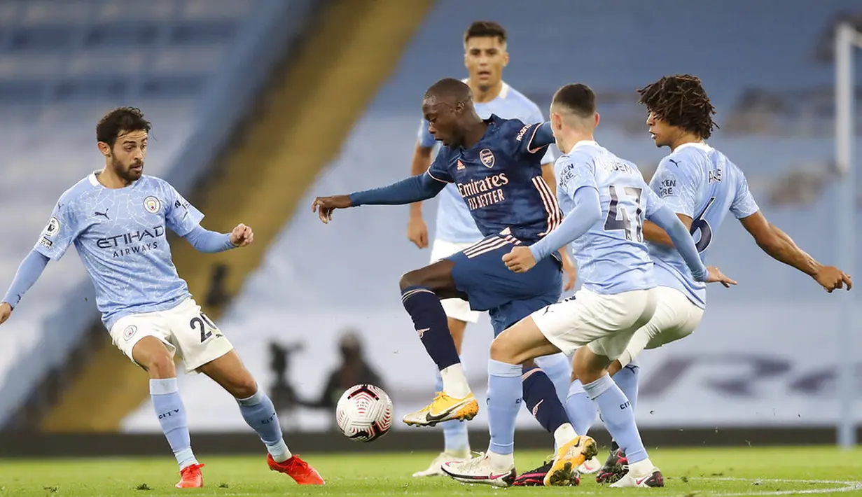 Pemain Arsenal Nicolas Pepe (tengah) menirin bola melewati para pemain Manchester City pada pertandingan Liga Premier Inggris di Etihad Stadium, Manchester, Inggris, Sabtu (17/10/2020). Manchester City menang 1-0. (Martin Rickett/Pool via AP)