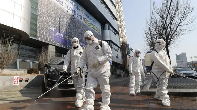 Para pekerja yang mengenakan pakaian pelindung menyemprotkan desinfektan terhadap virus corona baru di depan sebuah gereja di Daegu, Korea Selatan, Kamis, 20 Februari 2020.