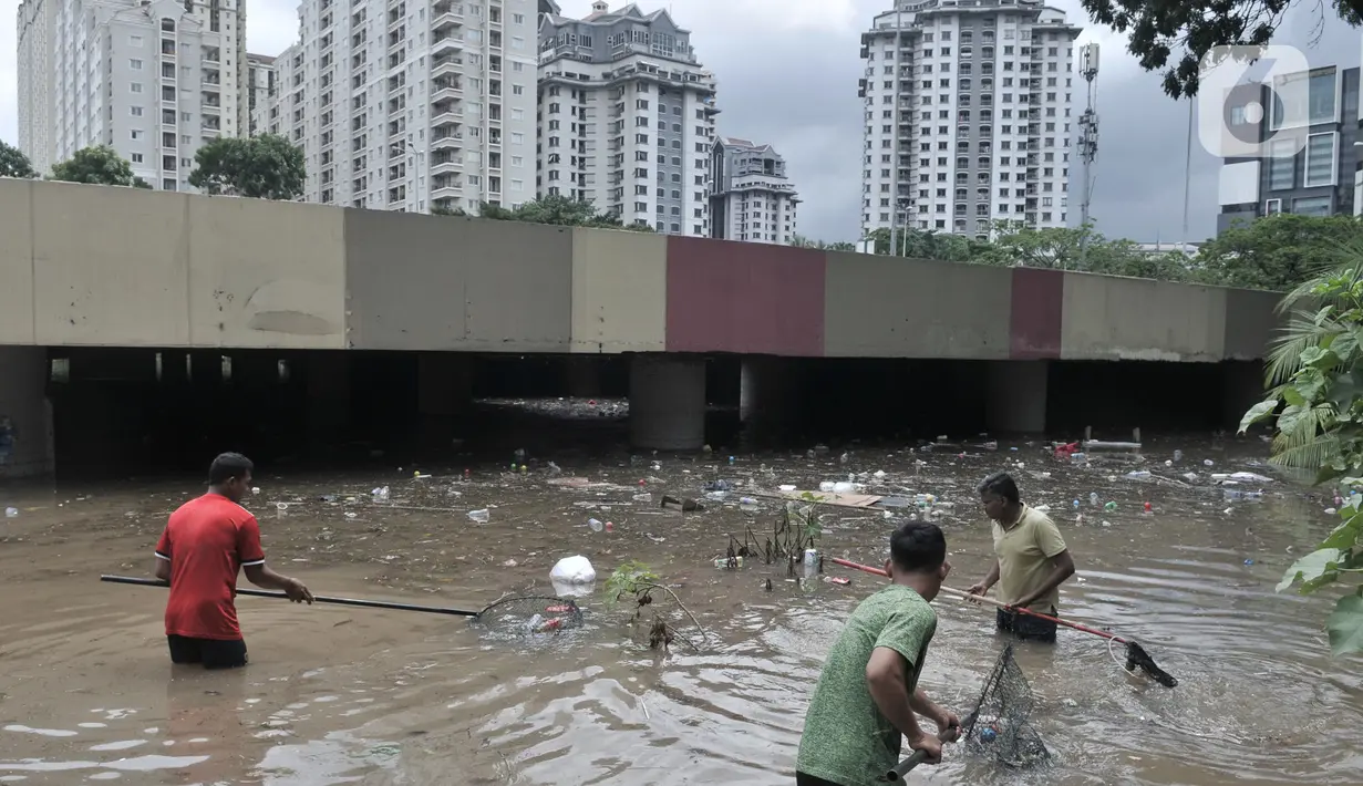 Petugas Pusat Pengelolaan Kompleks (PPK) Kemayoran membersihkan sampah yang muncul akibat banjir di Underpass Kemayoran, Jakarta, Minggu (2/2/2020). Selain melumpuhkan akses, banjir setinggi hingga 5 meter tersebut menyebabkan sampah memenuhi Underpass Kemayoran. (merdeka.com/Iqbal S. Nugroho)