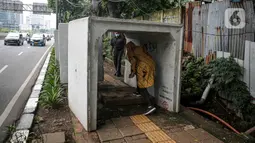 Pejalan kaki melintas di antara beton saluaran air yang berada di jalur pedestrian kawasan Gatot Subroto, Jakarta, Selasa (21/12/2021). Selain mengganggu kenyamanan, keberadaan beton saluran air tersebut juga dapat membahayakan pejalan kaki yang melintas. (Liputan6.com/Faizal Fanani)