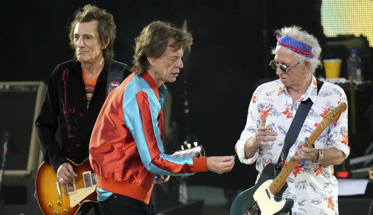 <p>Penyanyi band The Rolling Stones Mick Jagger (tengah) menyerahkan plektrum baru kepada gitaris Keith Richards (kanan) saat konser Sixty di Berlin, Jerman, 3 Agustus 2022. Tur Sixty mencakup 14 konser di seluruh benua. (AP Photo/Michael Sohn)</p>