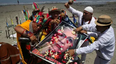 Seorang dukun Peru menyiram perasan buah pada poster bergambar Capres AS dari Partai Demokrat, Hillary Clinton saat melakukan ritual prediksi menjelang pemilihan presiden AS, di Lima, Peru, Senin (7/11). (REUTERS/Mariana Bazo)