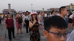 Warga berjalan menghadiri upacara pengibaran bendera saat fajar setelah kematian mantan perdana menteri China Li Peng di Lapangan Tiananmen Beijing (24/7/2019). Li Peng biasa dikenal sebagai "Jagal Beijing" meninggal di usia 90 tahun. (AFP Photo/Greg Baker)
