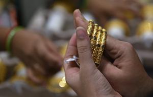 Seorang pelanggan mencoba gelang emas selama festival Hindu 'Akshaya Tritiya', hari keberuntungan dalam kalender Hindu untuk membeli barang-barang berharga, di ruang pamer perhiasan di Chennai, India, Selasa (3/5/2022). Membeli emas adalah kegiatan yang populer di Akshaya Tritiya, karena ini adalah simbol utama kekayaan dan kemakmuran. (Arun SANKAR / AFP)