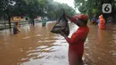 Warga menunjukkan ikan hasil menjala di tengah jalan yang tertutup banjir di kawasan TB Simatupang, Jakarta Selatan, Sabtu (20/2/2021). Banjir terjadi akibat luapan Kali Serua yang berada di pinggir jalan tol. (merdeka.com/Arie Basuki)