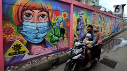 Pengendara sepeda motor melintasi mural bertema COVID-19 di kawasan Tanah Tinggi, Tangerang, Banten, Rabu (20/1/2020). Kegiatan ini dalam rangka mensosialisasikan bahaya penyebaran COVID-19 kepada warga pengguna jalan umum. (merdeka.com/Arie Basuki)