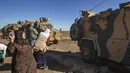 Seorang wanita Kurdi melemparkan batu ke kendaraan militer Turki di dekat kota Al-Muabbadah, bagian timur laut Hassakah, Suriah (8/11/2019). Pelemparan batu terjadi saat militer Turki melakukan konvoi dengan militer Rusia. (AFP/Delil Souleiman)