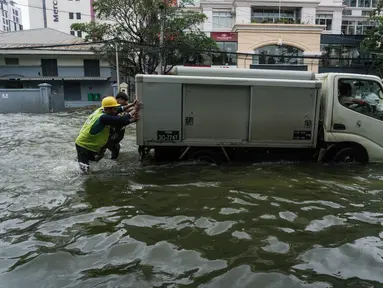 Orang-orang mendorong kendaraan yang mogok di jalan yang banjir di pinggiran Yangon, Myanmar  (17/8/2022). Hujan lebat sejak larut malam 16 Agustus menyebabkan kemacetan lalu lintas dan kesulitan bagi para komuter di kota Yangon dengan beberapa jalan masih terendam banjir.  (AFP/Stringer)