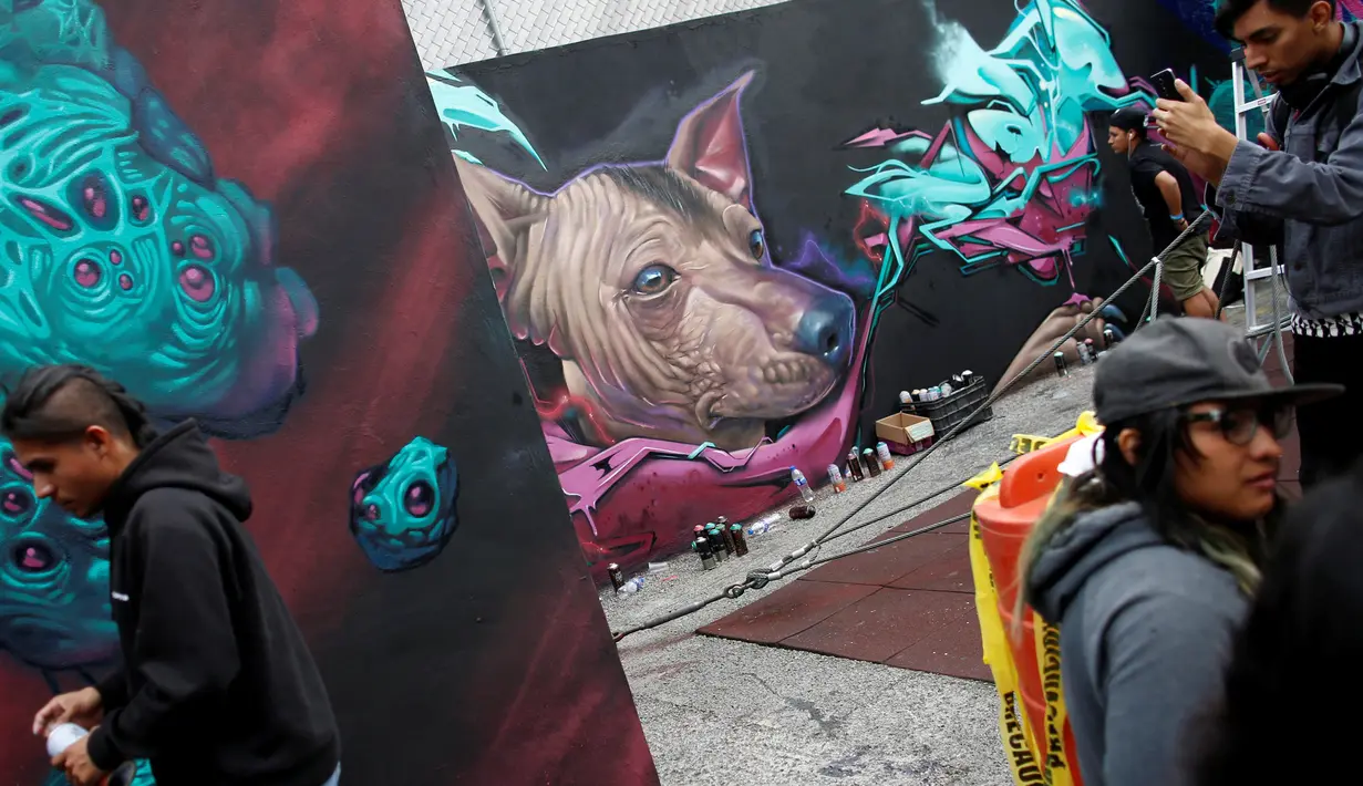 Pengunjung menikmati karya para seniman grafiti yang warnanya berdominan violet di Mexico City, Meksiko, Minggu (9/10). Seni jalanan ini biasanya memang dibuat di tembok-tembok jalan kota. (REUTERS/Carlos JASSO)