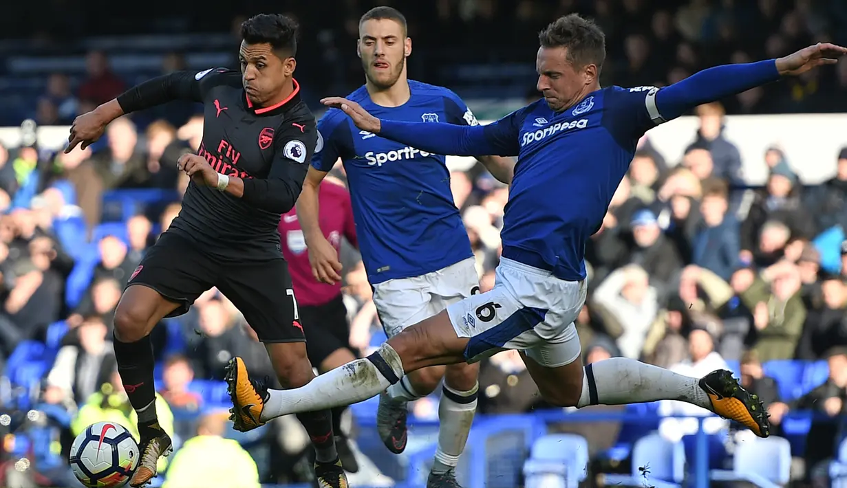 Pemain Arsenal, Alexis Sanchez (kiri) mencoba melewati adangan pemain Everton, Phil Jagielka (kanan) pada laga Premier League pekan ke-9 di Goodison Park, Liverpool, (22/10/2017). Arsenal menang 5-2. (AFP/Oli Scarff)
