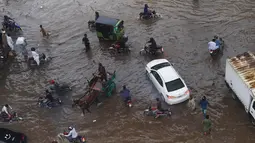 Sejumlah warga melintasi banjir saat beraktivitas setelah hujan deras di Lahore, Pakistan (16/7/2019). Di Kashmir yang dikelola Pakistan, para pejabat pemerintah mengatakan sedikitnya 23 orang tewas setelah hujan lebat memicu banjir bandang. (AFP Photo/Arif Ali)