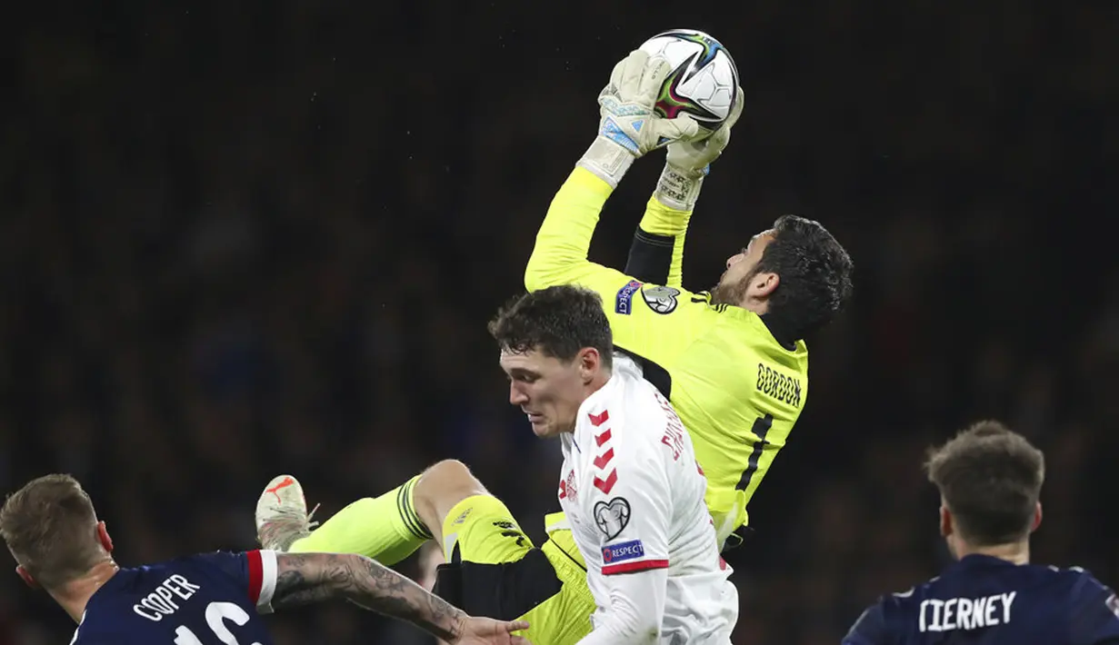Penjaga gawang Skotlandia Craig Gordon (atas) menangkap bola di bawah tekanan dari pemain Denmark Andreas Christensen pada pertandingan sepak bola kualifikasi Grup F Piala Dunia 2022 di Stadion Hampden Park, Glasgow, Skotlandia, 15 November 2021. Skotlandia menang 2-0. (AP Photo/Scott Heppell)