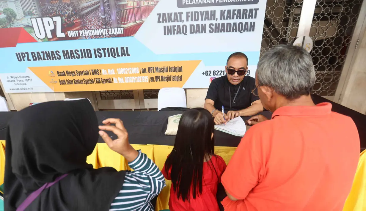 Petugas Unit Pengelola Zakat (UPZ) melayani pembayaran zakat, fidyah, kafarat, infaq, dan shadaqah di teras Masjid Istiqlal, Jakarta, Minggu 15 Maret 2026. Selain menjalankan ibadah selama bulan suci Ramadan, umat muslim juga diwajibkan untuk menunaikan zakat fitrah. (Kapanlagi.com/Budy Santoso)