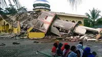 Sejumlah warga berkumpul di luar sebuah masjid yang mengalami kerusakan akibat gempa yang mengguncang  Kabupaten Pidie Jaya, Aceh, Rabu (7/12). Seperti dirilis BMKG, gempa berkekuatan 6,4 SR mengguncang Aceh sekitar pukul 05.03 WIB. (Zian Muttaqien/AFP)