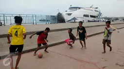 Seorang berusaha mengontrol bola saat bermain bola di pelataran Pelabuhan Kali Adem, Muara Angke, Jakarta, Rabu (4/1). Mereka memanfaatkan Pelabuhan Kali Adem sebagai arena bermain selama mengisi masa liburan sekolah. (Liputan6.com/Gempur M Surya)