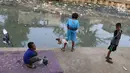 Anak-anak bermain di bantaran anak Sungai Ciliwung, Jakarta, Rabu (6/6). Meskipun tidak layak sebagai tempat bermain, namun lokasi itu menjadi tempat bagi anak-anak di kawasan tersebut untuk menunggu waktu berbuka. (Liputan6.com/Immanuel Antonius)