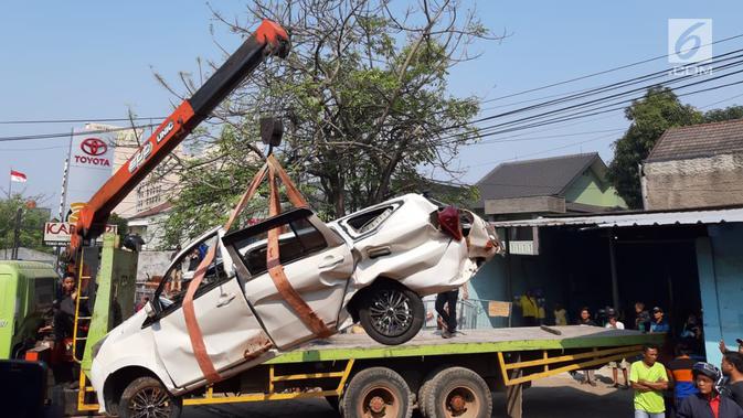 Petugas derek mengevakuasi bangkai mobil kecelakaan maut yang hancur tertindih badan truk muatan tanah di Karawaci, Tangerang, Kamis (1/8/2019). Lima orang penumpang minibus menjadi korban, empat diantaranya meninggal dan satu balita berhasil diselamatkan warga. (Liputan6.com/Pramita Tristiawati)