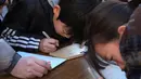 Pelajar menulis harapan mereka di atas papan Ema di Kuil Yushima Tenmangu, Tokyo, Jepang, (7/1). Mereka menuliskan harapan di atas papan Ema agar diberikan kemudahan dalam menghadapi ujian masuk sekolah tahun ini. (AFP Photo/Kazuhiro Nogi)