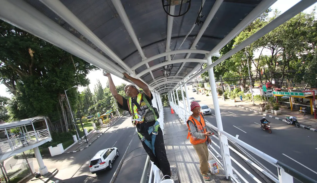 Pekerja mengecat pagar dan atap jembatan penyeberangan menuju halte Transjakarta di kawasan Cawang, Jakarta, Rabu (5/4). Pengecatan dilakukan untuk menjaga halte agar tetap bersih dan terawat. (Liputan6.com/Immanuel Antonius)