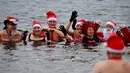 Para anggota klub renang "Berliner Seehunde" (Berlin Seals) berendam di Danau Orankesee sebagai bagian dari tradisi berenang pada Natal di Berlin, Senin (25/12). Kegiatan ini salah satu tradisi di Berlin menyambut Natal setiap tahun (Tobias SCHWARZ/AFP)