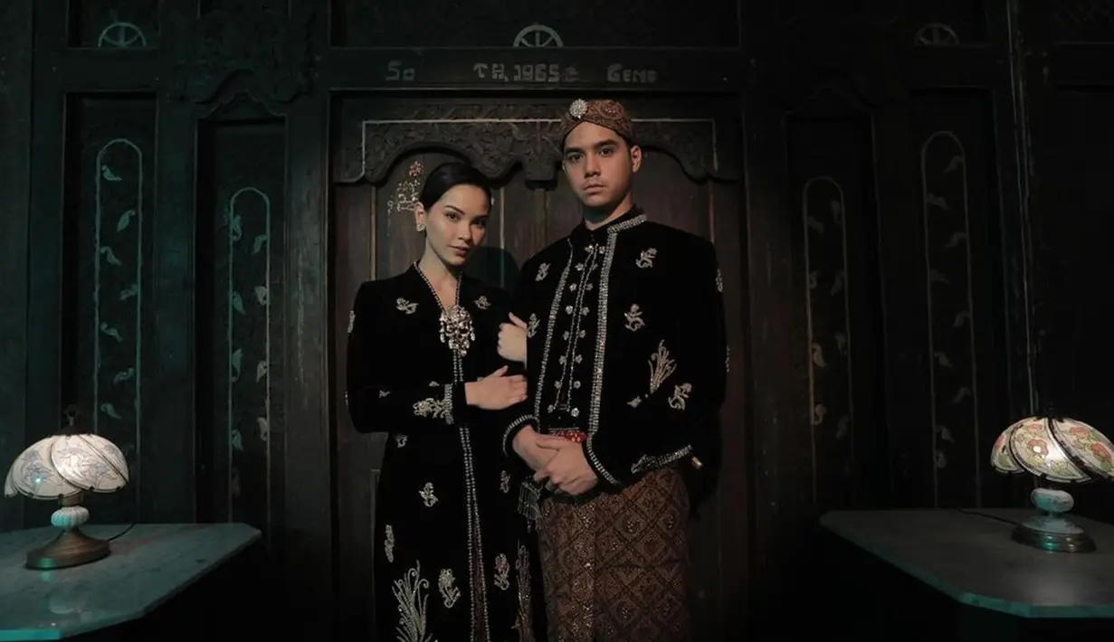 Seperti biasanya, Al Ghazali tampil gagah dalam balutan beskap hitam berbahan velvet. Dilengkapi pula dengan blangkon batik dan bros silver. Sementara, Alyssa tampil elegan dengan kebaya kartini. Motif busana yang dikenakan keduanya pun sama-sama bunga bernuansa emas. (Liputan6.com/IG/@alghazali7)